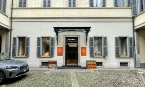 New Moynat Boutique Milan – Exterior facade with MOYNAT signage, heritage trunks and classic Milanese cobblestone street, photographed by Davide Palombo New Moynat Boutique Milan – Exterior Facade with Heritage Trunks on Milanese Cobblestone Street